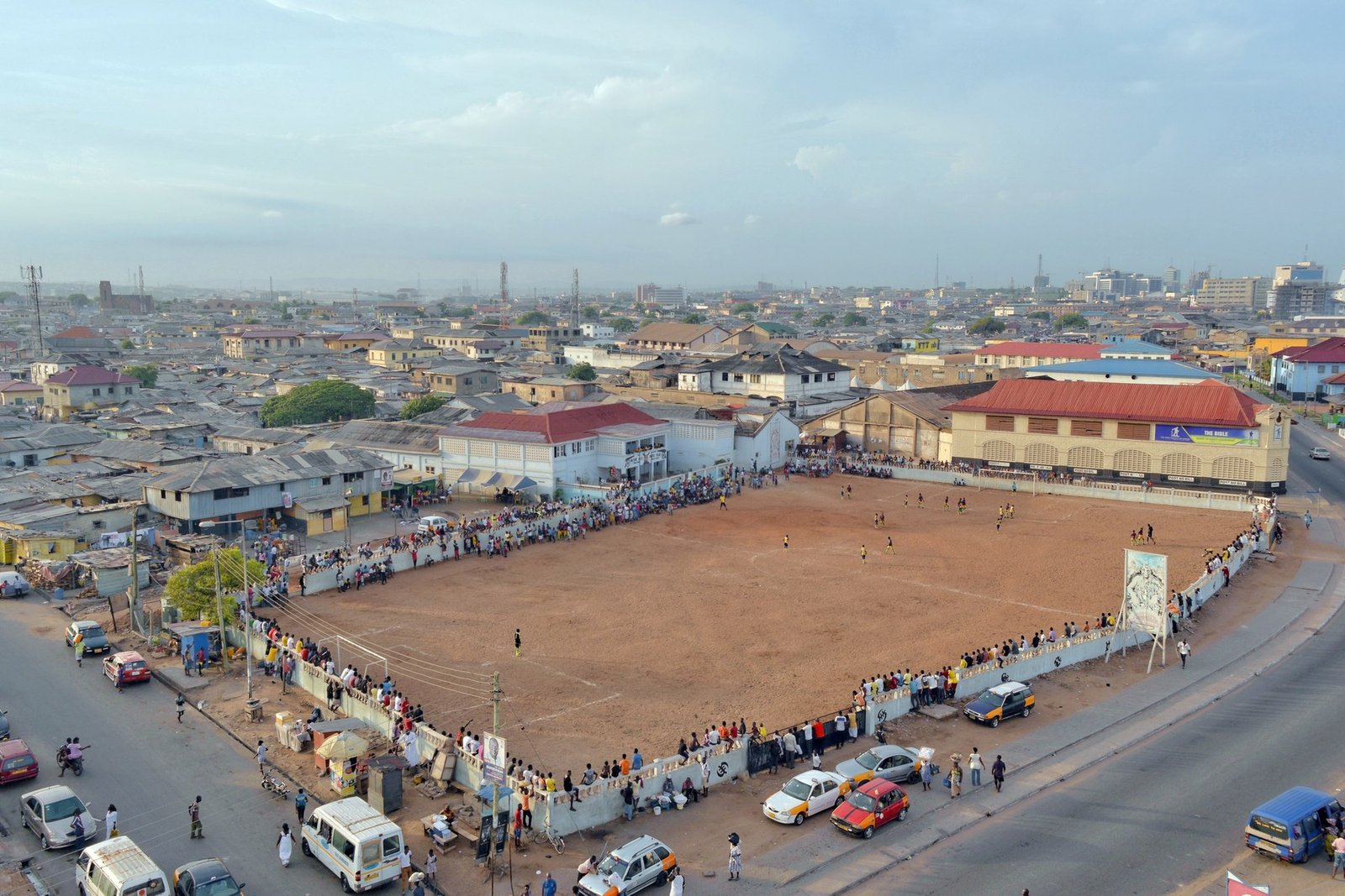 An elevated view of Jamestown, Accra, with homes, streets and a community football pitch.